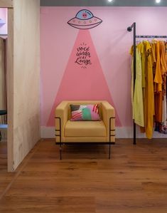 a room with pink walls and a yellow chair in front of a wall that has an advertisement on it