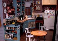 a small kitchen with blue cabinets and wooden table in front of the stove top oven