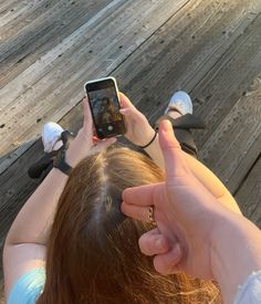 a woman is holding up her cell phone to take a selfie on the boardwalk