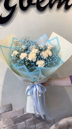 a person holding a bouquet of flowers in front of a sign that says gloen