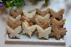 small sandwiches are arranged in the shape of bats on a plate next to some flowers