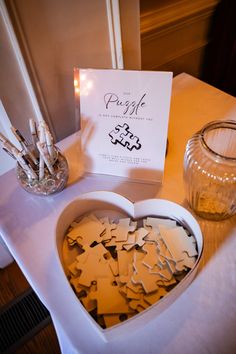 a heart shaped box filled with pieces of paper next to a candle and some candles