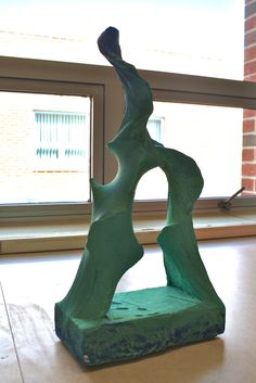 a green sculpture sitting on top of a table next to a window