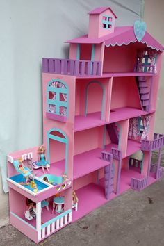 a pink and blue doll house next to a wall with dolls in the room on it