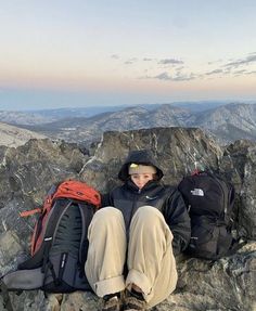 a person sitting on top of a mountain with backpacks