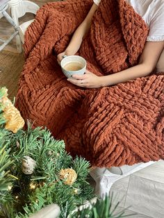 a woman wrapped in a blanket holding a cup of coffee