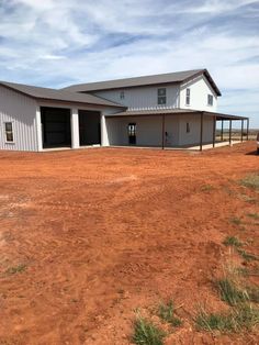 a large white building sitting in the middle of a dirt field next to a truck