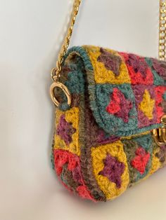 a multicolored crocheted purse hanging from a chain on a white surface