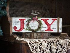 a wooden sign that says joy with a wreath on it