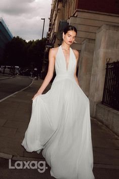 a woman in a white dress is walking down the street