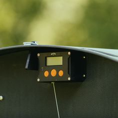 an electronic device is attached to the side of a vehicle's dashboard, with orange buttons