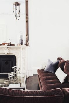 a living room filled with furniture and a fire place in front of a large mirror