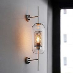 a light that is on the wall next to a glass vase with a candle in it