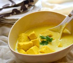 a yellow bowl filled with soup and tofu cubes on top of the broth