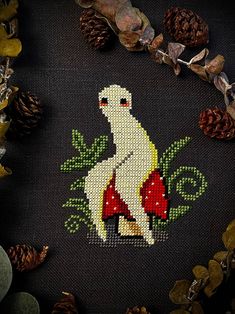 a cross - stitch picture of a white bird sitting on top of a mushroom