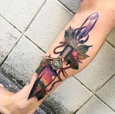 a man's leg with a tattoo on it that has a dagger and flowers