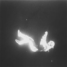 black and white photograph of a man falling off his snowboard in the air at night