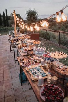 a long table filled with lots of food on top of a wooden table covered in lights