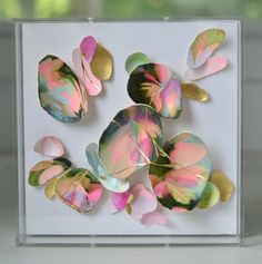 a close up of a paper plate with leaves on it in a clear box next to a window