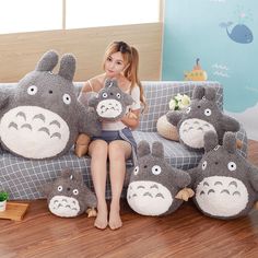 a woman is sitting on a couch with many stuffed animals in front of her,