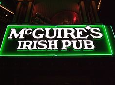 the sign for mcguire's irish pub is lit up in the dark