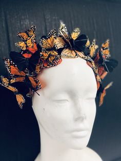 a white mannequin head with lots of orange and black butterflies on it's head