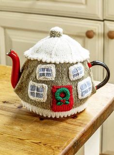 a knitted tea pot sitting on top of a wooden table