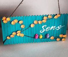 a wooden sign that says sense with birds and flowers painted on the front, hanging from twine strings