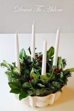 a white bowl filled with candles and greenery