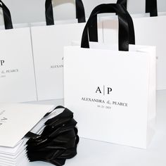 four white shopping bags sitting on top of each other next to some black and white paper