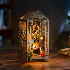 a miniature house made out of wood and glass sitting on a table next to a lamp