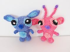 two crocheted stuffed animals sitting next to each other on a white table top