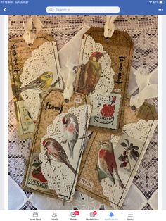 four tags with birds on them sitting on a lace doily covered tablecloth,