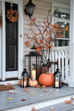 a porch decorated for fall with pumpkins and lanterns