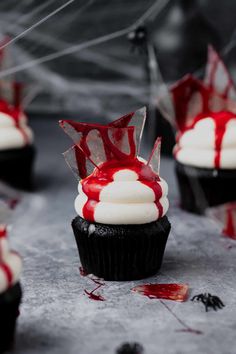 cupcakes with white frosting and red sprinkles are on the table