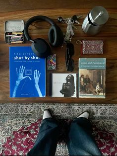 a person laying on the floor with headphones, books and other items