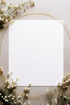 an empty paper surrounded by flowers on a white surface with gold trimmings and a square frame in the middle