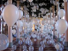 balloons are suspended from the ceiling in an art installation with white balls hanging from them