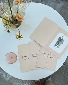 three cards on top of a white table next to a vase with flowers in it