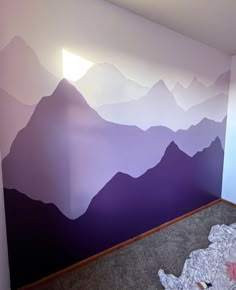 a room with mountains painted on the wall and carpeted flooring in front of it