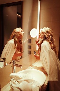 two women are brushing their teeth in front of the mirror while looking at each other's reflection