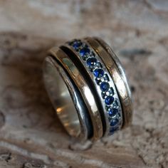 two wedding bands with blue and white stones on them sitting on a piece of wood