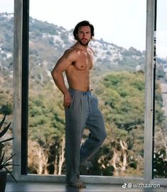 a man standing in front of a window with his shirt off and no shirt on