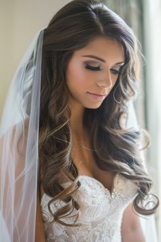 a woman in a wedding dress with a veil on her head and long hair wearing a tiara