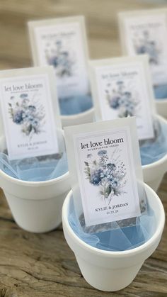 small white bowls filled with blue flowers on top of a wooden table next to each other