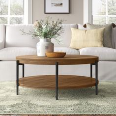 a living room with a white couch, coffee table and pillows on the carpeted floor