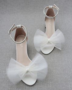 two pairs of white shoes with bows on the toes and one pair is made out of tulle