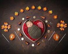 a newborn baby wrapped in a blanket surrounded by candles and candies on a table