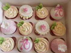 a box filled with lots of cupcakes covered in frosting and pink icing