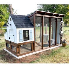 a chicken coop in the middle of a yard with an open door and windows on each side